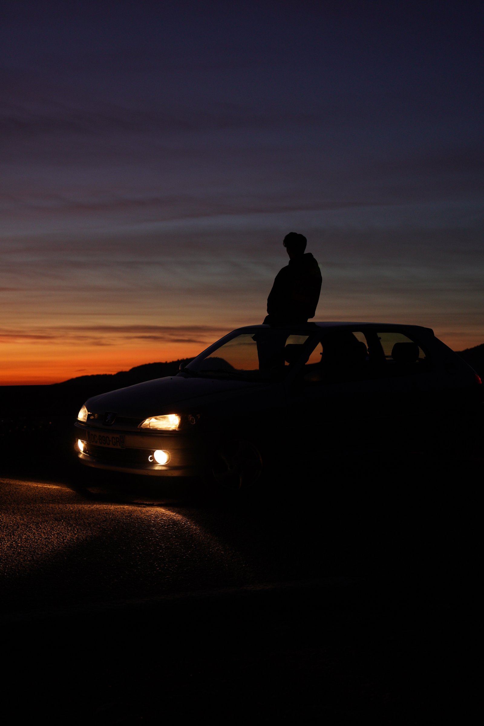 Silhouette sur le toit d'une voiture au crépuscule